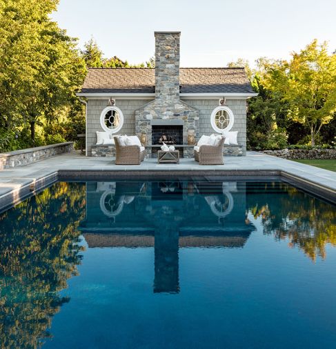 The pool house, whose shingled siding is color-matched to the main house, has nautical-themed Marvin windows sourced from Cherry Creek Windows & Doors.