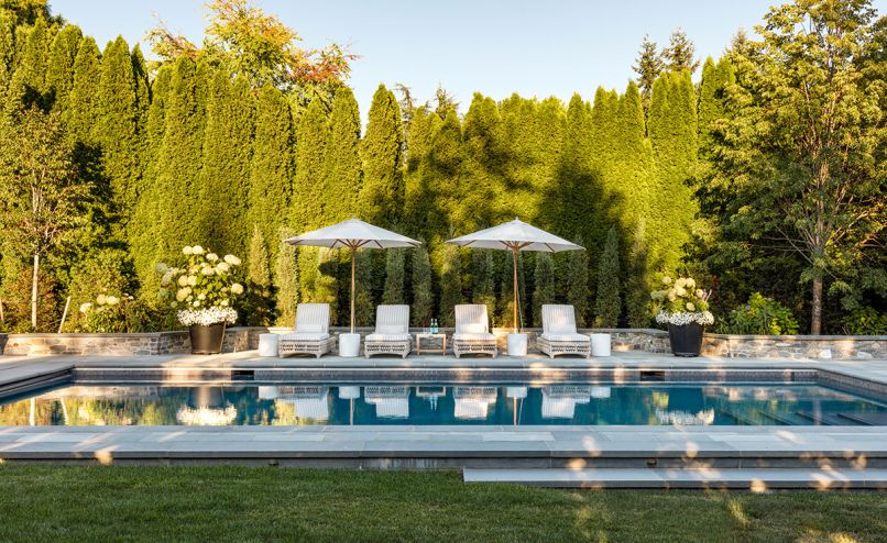 The cohesion throughout this backyard retreat is rooted in a thoughtful interplay of materials and layered plantings. Pennsylvania Bluestone pavers are paired with towering Arborvitae, Hydrangea &lsquo;Incrediball,&rsquo; and accents of Calibrachoa and Juniperus virginiana &lsquo;Taylor&rsquo; arranged in sculptural containers.