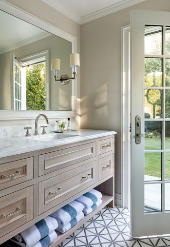 The simple yet sleek pool house bathroom combines wooden cabinetry with marble countertops for timeless, durable appeal, something the designer always infuses into her work.