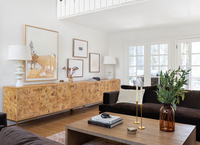 When filling a long space, two consoles are better than one, like in the living room where two burlwood pieces paired with a gallery wall.