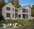 The exterior is covered in stained cedar siding, and combined with a standing seam metal roof. The Loewen windows and doors, from Windows, Doors & More, capture the stunning water views. Multiple lounge spots, on the shore and closer to the house, facilitate indoor-outdoor flow.