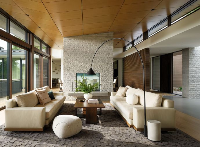 The living room fireplace has a two-sided DaVinci insert, and custom hand-split limestone from Arris Stoneworks Inc. The curved Miniforms Ozz Arc Lamp and Berman Rossetti Nobilis sofas make the room.