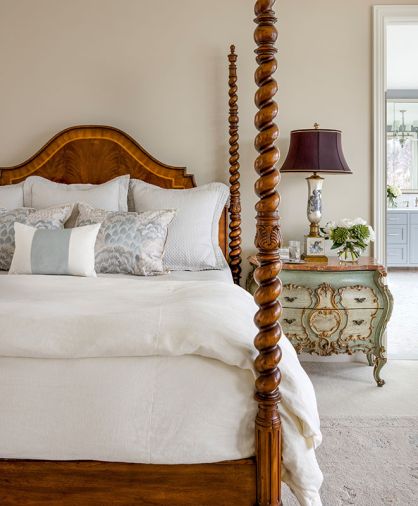 In the primary bedroom, the owner&rsquo;s bedframe was refreshed with linens from Legacy Linens, Trammell Gagne, and Pindler. The walls have a custom color and are paired with an antique dresser.