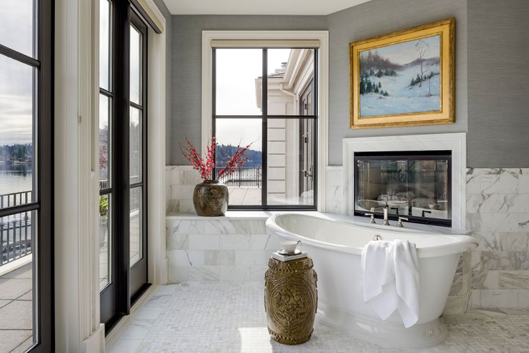 The freestanding Artifacts tub from Kohler offers views of the water and makes for a pleasing vignette in front of the fireplace and surrounding Calacatta Gold Marble.