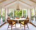 In the rebuilt breakfast room, Jessica Lane Interiors paired a custom sofa in Josef Frank&rsquo;s &ldquo;Exotic Butterfly&rdquo; fabric with a Saarinen-style table and retro rattan chairs with custom cushions. The vintage chandelier is from Hippo Hardware with a shade painted by Lonesome Pictopia.