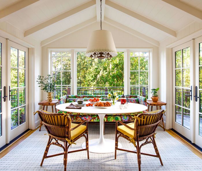 In the rebuilt breakfast room, Jessica Lane Interiors paired a custom sofa in Josef Frank&rsquo;s &ldquo;Exotic Butterfly&rdquo; fabric with a Saarinen-style table and retro rattan chairs with custom cushions. The vintage chandelier is from Hippo Hardware with a shade painted by Lonesome Pictopia.