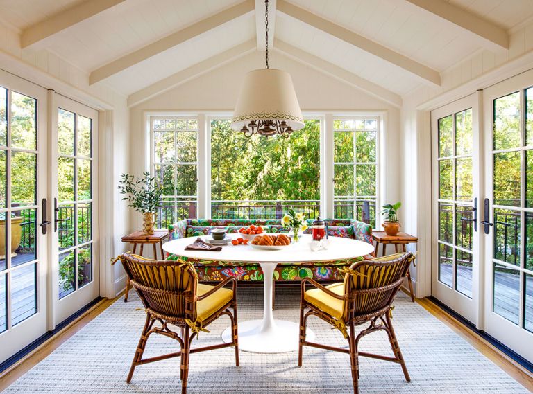 In the rebuilt breakfast room, Jessica Lane Interiors paired a custom sofa in Josef Frank&rsquo;s &ldquo;Exotic Butterfly&rdquo; fabric with a Saarinen-style table and retro rattan chairs with custom cushions. The vintage chandelier is from Hippo Hardware with a shade painted by Lonesome Pictopia.