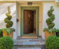 The entry has a custom copper door with rivet details, variegated bluestone, and select boxwood topiary.