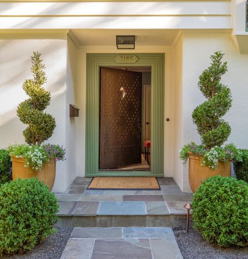 The entry has a custom copper door with rivet details, variegated bluestone, and select boxwood topiary.