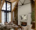 In the great room, the soft-brown tumbled sandstone is rustic against the plaster fireplace. Traditional Lee Industries sofas were sourced from J Garner Home and diamond-patterned armchairs from Nicky Kehoe.
