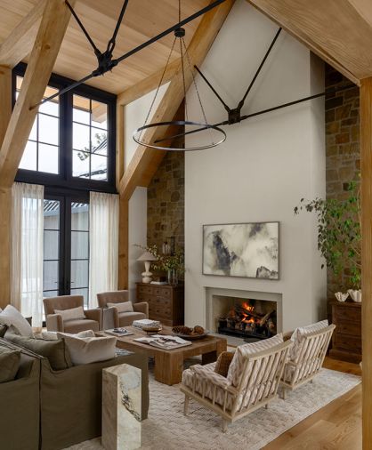 In the great room, the soft-brown tumbled sandstone is rustic against the plaster fireplace. Traditional Lee Industries sofas were sourced from J Garner Home and diamond-patterned armchairs from Nicky Kehoe.