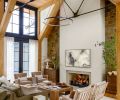 In the great room, the soft-brown tumbled sandstone is rustic against the plaster fireplace. Traditional Lee Industries sofas were sourced from J Garner Home and diamond-patterned armchairs from Nicky Kehoe.