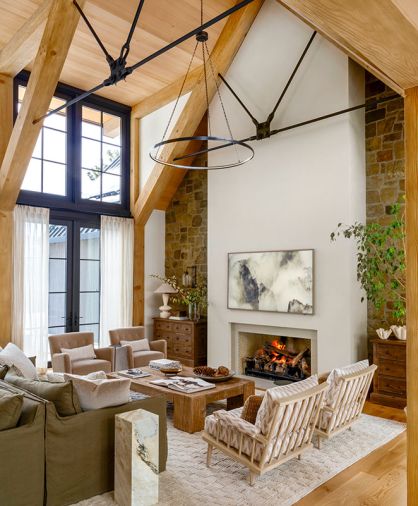 In the great room, the soft-brown tumbled sandstone is rustic against the plaster fireplace. Traditional Lee Industries sofas were sourced from J Garner Home and diamond-patterned armchairs from Nicky Kehoe.