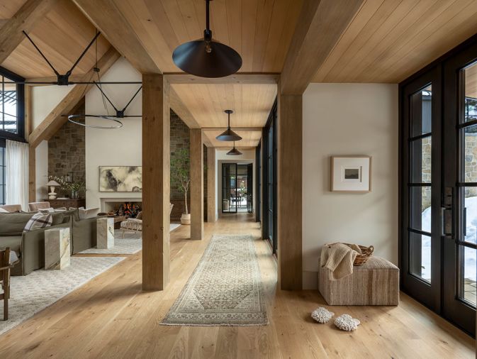 The project team brought in a medley of woods to anchor the main room, from the timber trusses to the white oak flooring found throughout, which is from Montello Design .The pendant lights are from CB2 and lining the walkway is a soft neutral runner underfoot.