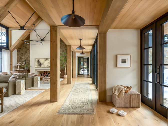 The project team brought in a medley of woods to anchor the main room, from the timber trusses to the white oak flooring found throughout, which is from Montello Design .The pendant lights are from CB2 and lining the walkway is a soft neutral runner underfoot.