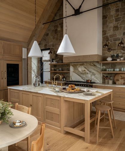 Custom floating shelves, crafted by Artisan Inc., flank the Lacanche range, adding both function and warmth to the space. Conical pendants from The Lamp Workshop hang above the island and sink, illuminating the exquisite House of Rohl plumbing fixtures.