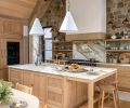 Custom floating shelves, crafted by Artisan Inc., flank the Lacanche range, adding both function and warmth to the space. Conical pendants from The Lamp Workshop hang above the island and sink, illuminating the exquisite House of Rohl plumbing fixtures.