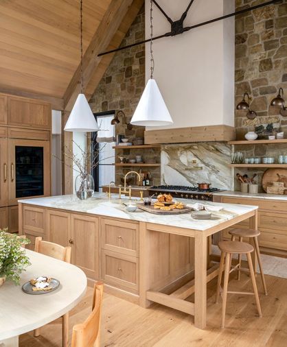 Custom floating shelves, crafted by Artisan Inc., flank the Lacanche range, adding both function and warmth to the space. Conical pendants from The Lamp Workshop hang above the island and sink, illuminating the exquisite House of Rohl plumbing fixtures.
