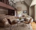 In the &ldquo;Summer Room,&rdquo; Artisan Inc. installed custom bunks using cabinetry by Crystal Cabinets, painted in Sherwin Williams &ldquo;Velvety Chestnut.&rdquo; The walls are painted in Benjamin Moore &ldquo;Ballet White,&rdquo; as a backdrop for the textural Lee Industries sofa from J Garner Home.