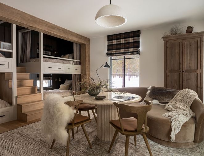 In the &ldquo;Fall Room,&rdquo; Artisan Inc. fashioned custom stairs between the bunks for easy access to the top bunks. At the travertine table, the Four Hands chairs are from J Garner Home and are atop a wool rug. The custom wardrobe is from Vintage Mill Werks.