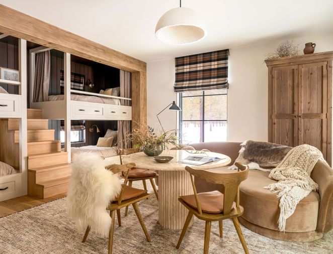 In the &ldquo;Fall Room,&rdquo; Artisan Inc. fashioned custom stairs between the bunks for easy access to the top bunks. At the travertine table, the Four Hands chairs are from J Garner Home and are atop a wool rug. The custom wardrobe is from Vintage Mill Werks.