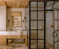 Lawton sourced the antique, tumbled limestone from Francois & Co. Handmade Zellige clay tile from Cle Tile lines the black paned primary bathroom shower, while the custom medicine cabinet in white oak is by Artisan Inc. The sconces that flank either side are from Visual Comfort & Co.