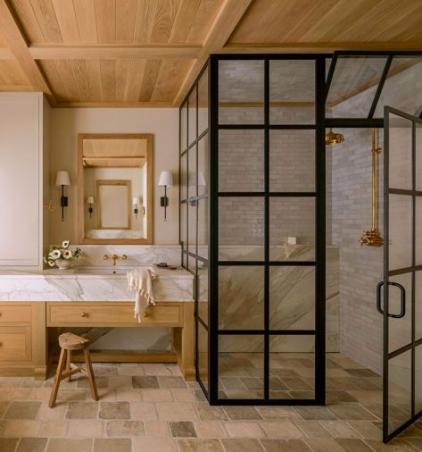 Lawton sourced the antique, tumbled limestone from Francois & Co. Handmade Zellige clay tile from Cle Tile lines the black paned primary bathroom shower, while the custom medicine cabinet in white oak is by Artisan Inc. The sconces that flank either side are from Visual Comfort & Co.