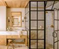 Lawton sourced the antique, tumbled limestone from Francois & Co. Handmade Zellige clay tile from Cle Tile lines the black paned primary bathroom shower, while the custom medicine cabinet in white oak is by Artisan Inc. The sconces that flank either side are from Visual Comfort & Co.