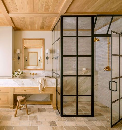 Lawton sourced the antique, tumbled limestone from Francois & Co. Handmade Zellige clay tile from Cle Tile lines the black paned primary bathroom shower, while the custom medicine cabinet in white oak is by Artisan Inc. The sconces that flank either side are from Visual Comfort & Co.