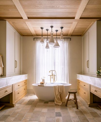 The custom ceiling is composed of waxed white oak tongue and groove and shallow box beams. Handmade clay pendants by Natalie Page Studio hang above the cement soaking tub and House of Rohl tub filler.