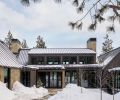 The exterior is covered in neutral sandstone from Select Stone, juxtaposed to the dark siding. A standing seam metal roof protects from harsh weather and prevents deep snow from accumulating on top of the home. Bisom Landscape Architecture LLC helped create a welcoming entrance and designed the surrounding landscape.