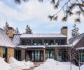 The exterior is covered in neutral sandstone from Select Stone, juxtaposed to the dark siding. A standing seam metal roof protects from harsh weather and prevents deep snow from accumulating on top of the home. Bisom Landscape Architecture LLC helped create a welcoming entrance and designed the surrounding landscape.