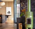 In the living room, the La Castellamonte Roundstack Slim stove in &ldquo;Verde&rdquo; is placed before a wall covered in &ldquo;Coal Creek&rdquo; clay bricks from Mutual Materials.