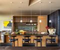 The nature-inspired kitchen backsplash is Makoto tile in &ldquo;Midori Green&rdquo; from Bedrosians Tile & Stone, is balanced with stained white oak cabinetry with a custom veneer grain. The living room in the background reveals a Gentry sofa by Patricia Urquiota from Moroso under artwork by Pat McKay.