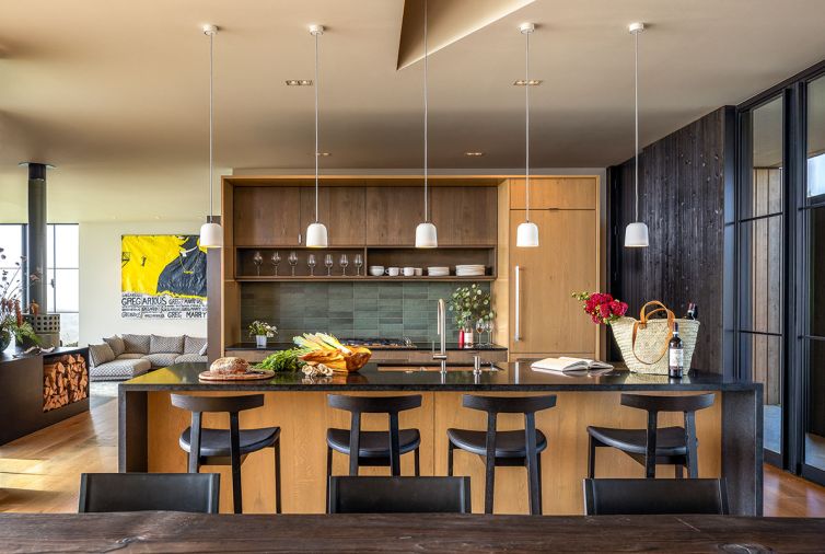 The nature-inspired kitchen backsplash is Makoto tile in &ldquo;Midori Green&rdquo; from Bedrosians Tile & Stone, is balanced with stained white oak cabinetry with a custom veneer grain. The living room in the background reveals a Gentry sofa by Patricia Urquiota from Moroso under artwork by Pat McKay.