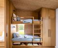 The built-in bunk beds are fashioned from the same white oak as the kitchen, with Enna Square wall sconces from Astro Lighting, Munich Collection hardware, and linens from Ventidora.