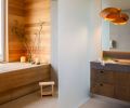 The floating vanity has stained white oak cabinetry and a Basaltina counter, with &ldquo;Bateig Blue&rdquo; tile from Ann Sacks on the floor.