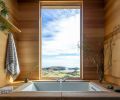In the primary bathroom, a tub from Kohler is ensconced in cedar, with a Willis waterfall Roman tub faucet from Signature Hardware.