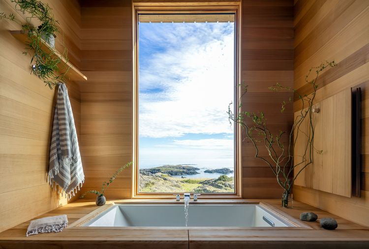 In the primary bathroom, a tub from Kohler is ensconced in cedar, with a Willis waterfall Roman tub faucet from Signature Hardware.