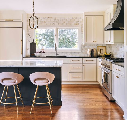 Elegant cabinetry enrobes JennAir appliances, a Delta faucet, and an Elkay sink, all sourced from Ferguson. Daltile Calacatta gold wall tile sparkles, popping against island cabinetry painted in Benjamin Moore&rsquo;s &ldquo;Black Jack.&rdquo;