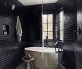Grounding the wet shower and bath is eye catching Mulholland Noir Blend Ann Sacks tile. K711 black matte tile from Rittenhouse enrobes a Signature Hardware Ocala tub with Hansgrohe Tecturis plumbing fixtures.