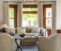 Saving the original woodwork after the fire was paramount to the homeowners, which are softened here with draperies from The Shade Store and rounded furnishings to add a feminine touch.