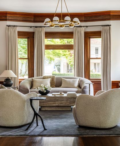 Saving the original woodwork after the fire was paramount to the homeowners, which are softened here with draperies from The Shade Store and rounded furnishings to add a feminine touch.