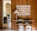 The entry has a console from Mitchell Gold + Bob Williams, and a stone floor from Ann Sacks. The antique shields on display conveys an immediate sense of history and quiet gravitas upon arrival.