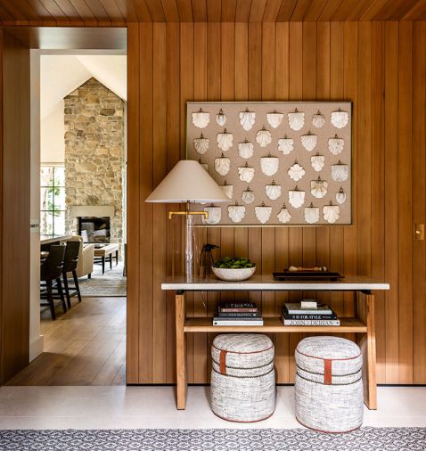 The entry has a console from Mitchell Gold + Bob Williams, and a stone floor from Ann Sacks. The antique shields on display conveys an immediate sense of history and quiet gravitas upon arrival.