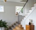 After Olson & Jones Construction gutted this 1910 Portland home, its staircase design was totally reconfigured to include Bright Designlab&rsquo;s sweeping multi-faceted trim and delicate stair railings manufactured by Sterling Steel Company. A Suki Porcini handwoven wool stair runner from Kush Rugs protects new treads. A Rosie Li Inez antique copper finished chandelier echoes the stair railing.