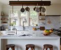 Built for a chef&rsquo;s pot collection, Bright Designlab&rsquo;s custom walnut rack with hidden LED lighting floats above Carrara marble counters. Eastbank Contractor Appliances supplied the Sub-Zero, Bosch, Miele, and Vent-A-Hood appliances; Sterling Steel Company built the rack with GKA Lighting.