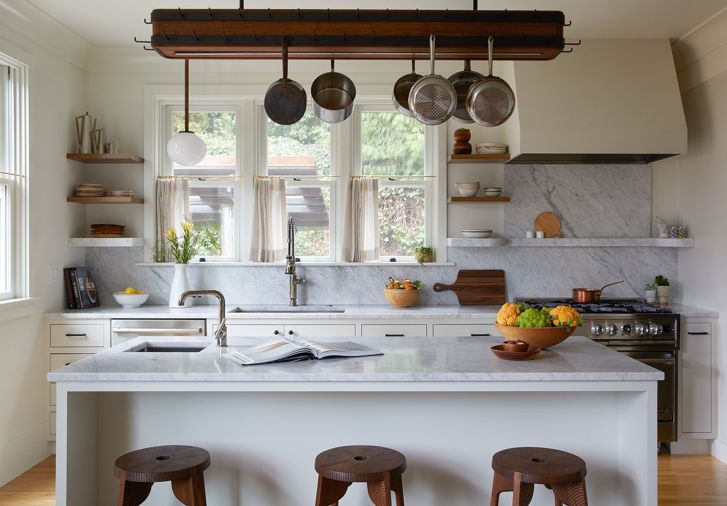 Built for a chef&rsquo;s pot collection, Bright Designlab&rsquo;s custom walnut rack with hidden LED lighting floats above Carrara marble counters. Eastbank Contractor Appliances supplied the Sub-Zero, Bosch, Miele, and Vent-A-Hood appliances; Sterling Steel Company built the rack with GKA Lighting.