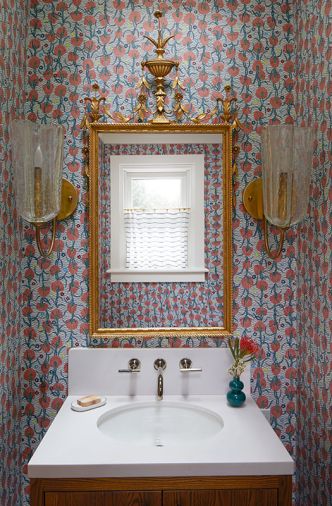 The powder room is trimmed in South African Watsonia Flower wallcovering by Pierre Frey. A gilded Grand Baroque mirror, Kohler sink and faucet, as well as custom vanity and cabinetry dress the room.