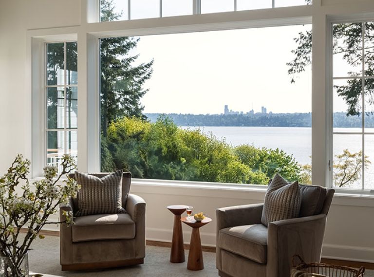 The new family room&rsquo;s Pella windows provide views of Seattle across Lake Washington. The comfy Wesley Hall Fremont swivel chairs and leather Durham storage ottoman are from DFG.